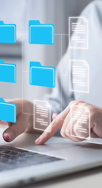 Krupni kadar ruku koje koriste prijenosno računalo uz virtualni prikaz digitalnog sustava s plavim mapama i povezanim dokumentima